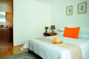 A hotel room with a bed, bedside table, lamp, framed pictures, and a small cabinet. - Torre Sevilla by The Local Way (Mexico City)