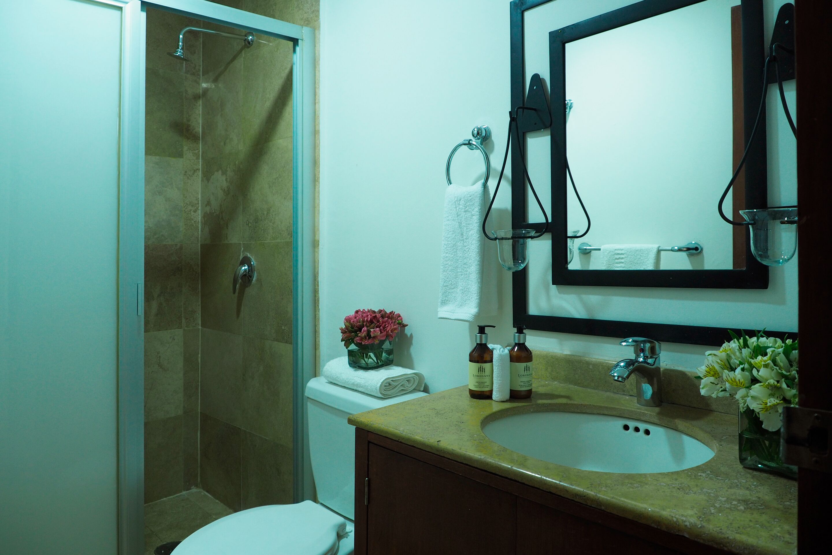 A bathroom with a shower, toilet, sink, and mirror.