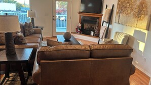 Een woonkamer met een bank, een salontafel, een open haard en een televisie.