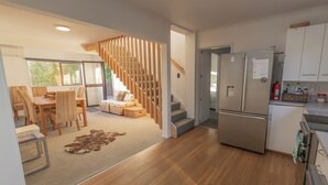 A modern kitchen with a built-in refrigerator, wooden flooring, and a dining area with wicker furniture.
