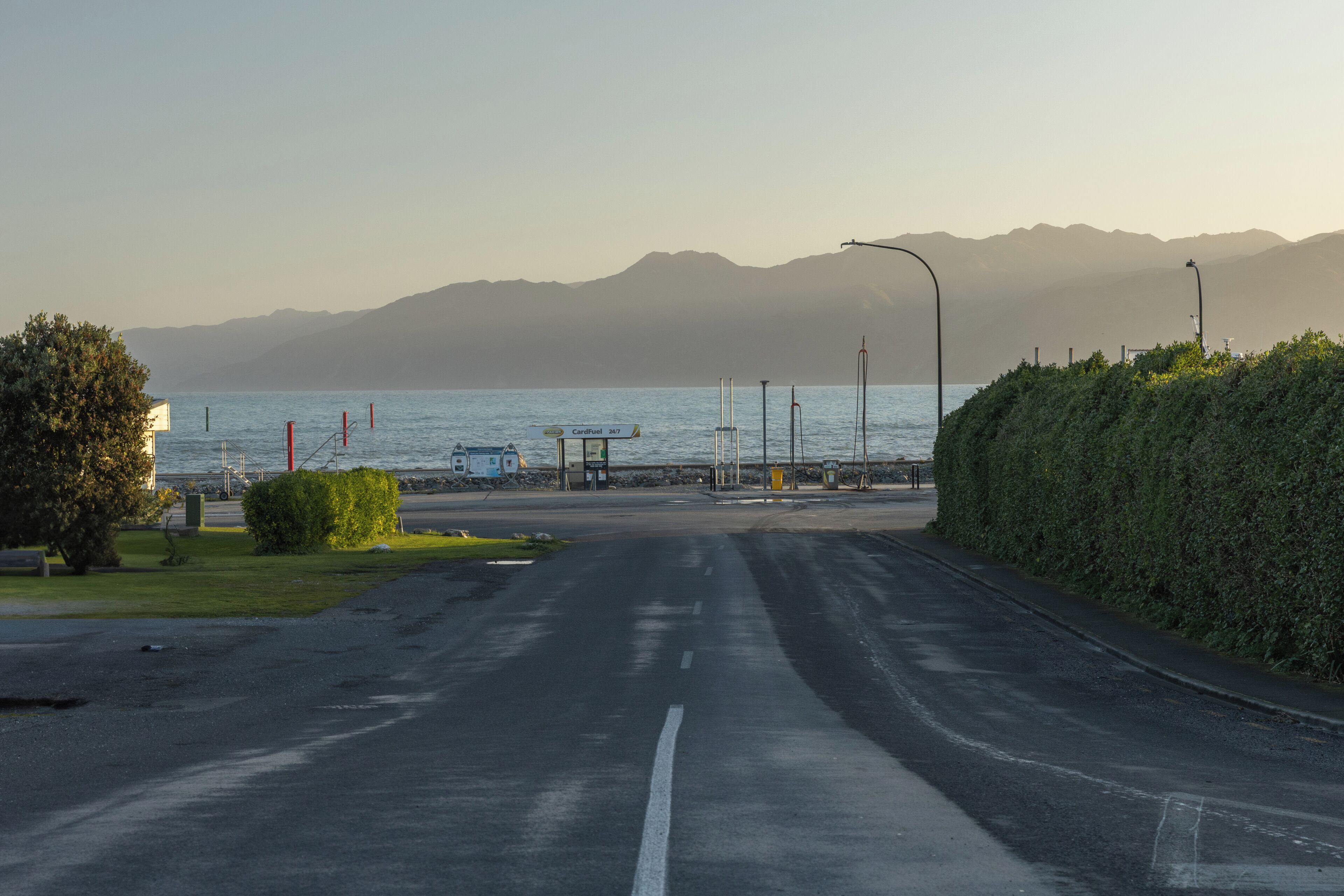 A coastal road with a clear view of the sea and mountains in the distance.