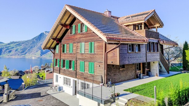 A wooden chalet with a sloped roof, a balcony, and a view of a lake and mountains. - Huus Chloster, Apt Niesen by Interhome (Krattigen)