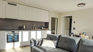 A modern kitchen with built-in appliances, a grey sofa, and a dining area with a table and chairs. - Huus Chloster, Apt Niesen by Interhome (Krattigen)