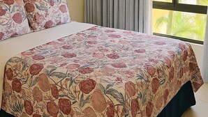Un dormitori amb un llit, una finestra gran amb cortines, un aparell d'aire condicionat i un quadre al mur.