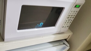 Fornet blanc amb pantalla digital i panell de control damunt d'un frigorífic blanc.