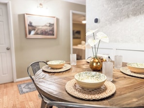 A dining table with placemats, bowls, and a vase with flowers.