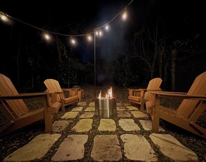 An outdoor seating area with Adirondack chairs and a fire pit.