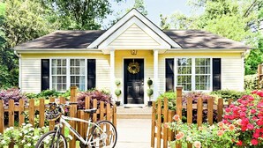 A yellow house with a front porch, a wooden fence, and a bicycle parked in front. - Curated & Caffeinated! Gem near Duke & Downtown • Espresso bar, Eco+, Fire Pit (Durham)