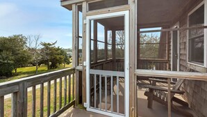 Une terrasse en bois avec une porte vitrée donnant sur un espace abrité.