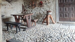 Ein rustikaler Innenraum mit Steinboden, Holzmöbeln und einer großen Holztür.
