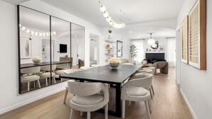 A modern dining area with a long table, multiple chairs, and a large mirror. - 2 Linked Suites • 6BR/6BA • Heated Pool/Spa • BBQ (Houston)