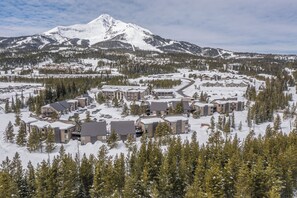 Ein schneebedecktes Resort mit mehreren Gebäuden, einer Skipiste und einem Berg im Hintergrund.