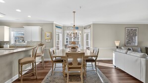 A spacious dining area with a large table, chairs, and a chandelier. - Modern Magnolia Pointe Condo Steps from the Beach | Magnolia Pointe Luster Leaf 4887-201 (Myrtle Beach)