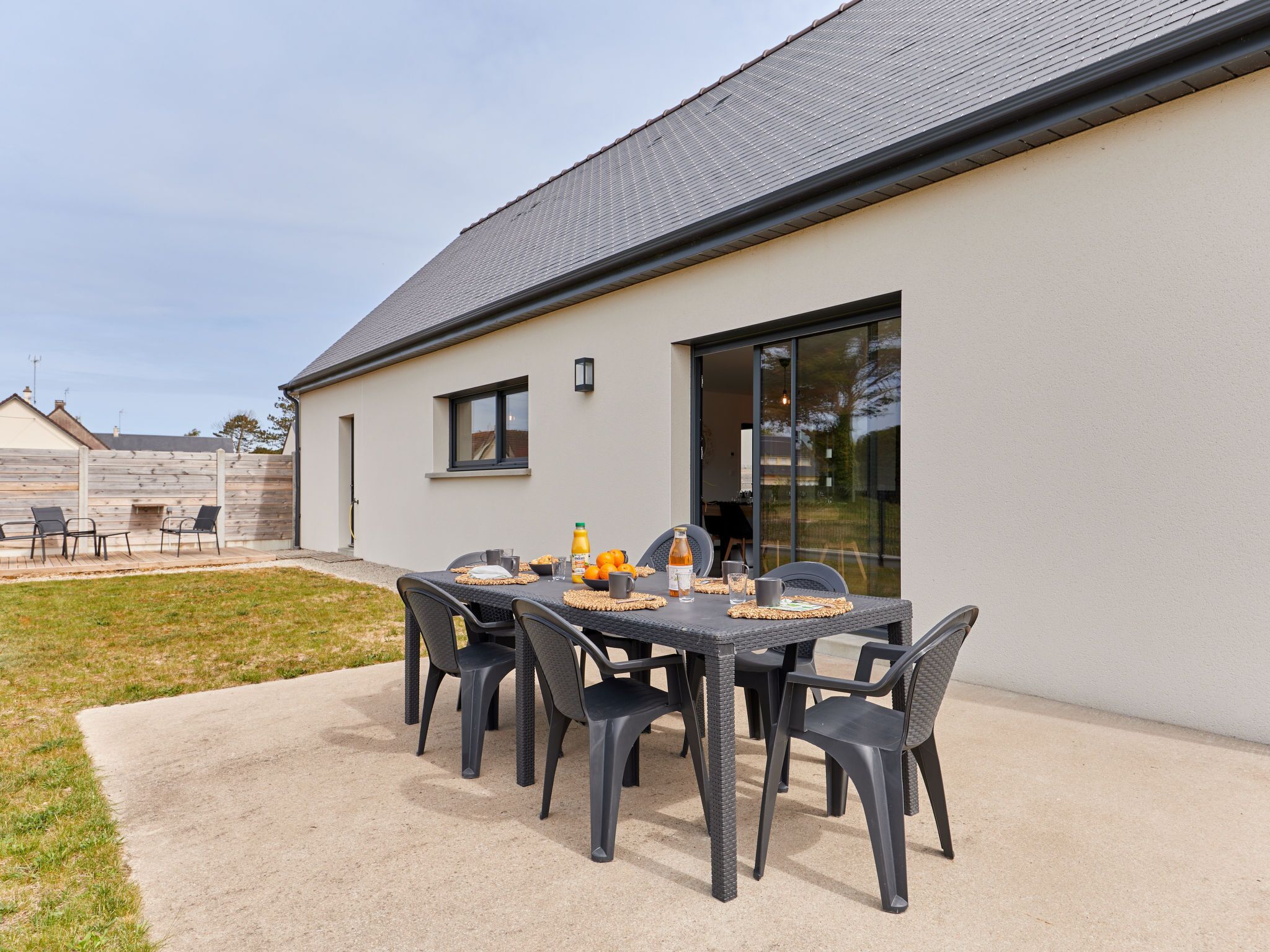 Une terrasse extérieure avec une table mise pour le petit-déjeuner, comprenant du jus d’orange et des viennoiseries.