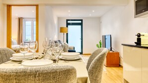 Un comedor moderno con una mesa dispuesta para cuatro personas, un televisor y una puerta que da a un balcón.