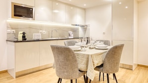 Una cocina moderna con microondas integrado, una cafetera y zona de comedor con mesa dispuesta para cuatro.