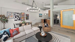 A modern living room with a sofa, coffee table, and artwork on the walls. - Designer Loft Penthouse in the Heart of Downtown (Pittsburgh)