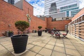 Un espace extérieur aménagé en patio, avec des murs en briques, des plantes en pot et des meubles de jardin.