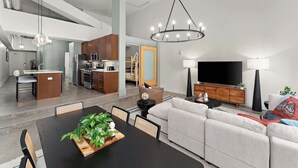 A modern living room with a dining area, kitchen, and a staircase leading to an upper level. - Designer Loft Penthouse in the Heart of Downtown (Pittsburgh)