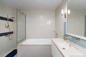 A modern bathroom with a glass-enclosed shower, a freestanding bathtub, and a sink with a mirror.