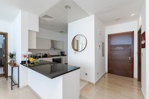 A modern kitchen with a central island, a round mirror on the wall, and a wooden door.