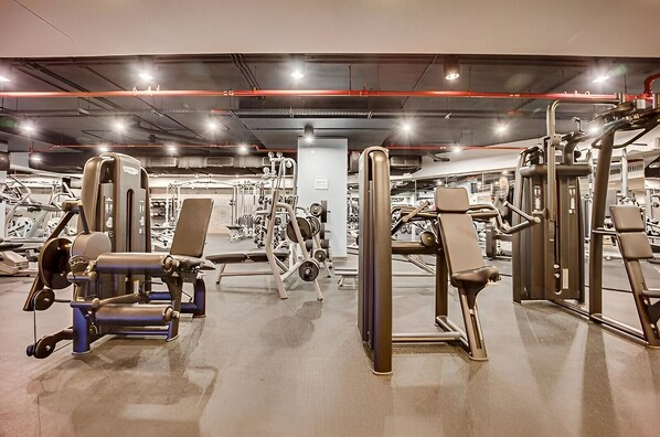 A gym with various exercise machines, including weight benches and free weights.