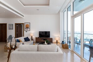 A modern living room with a sofa, TV, and large windows offering a city view.