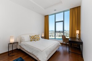 A modern hotel room with a large bed, a desk, and a view of the city.