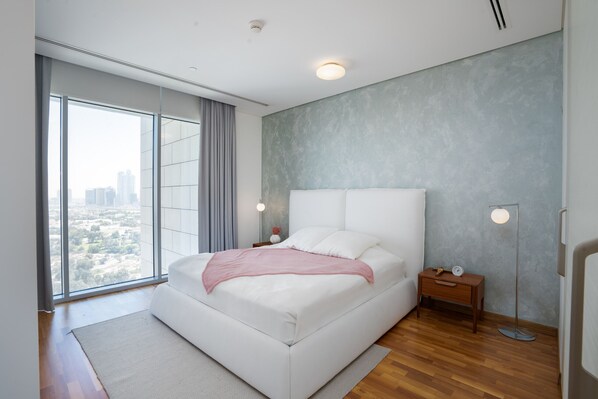 A modern bedroom with a large window, a bed, bedside tables, and a floor lamp.