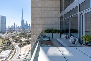 A modern balcony with seating and a view of the city skyline. - Cozy DIFC Duplex w/ Burj View, Pool and Gym (Dubai)