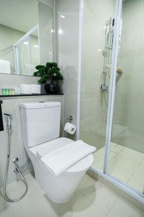 A modern bathroom with a toilet, bidet, and glass-enclosed shower stall.