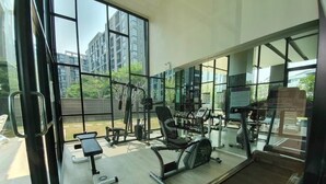 Ein Fitnessraum mit Trainingsgeräten, großen Fenstern und Blick auf Gebäude.