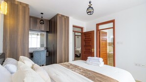 A hotel room with a large bed, a desk, and a wardrobe. - Spacious 3-bedroom apartment with WiFi, swimming pool in vibrant Tatu City (Tatu City)