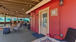 Une terrasse extérieure avec un foyer, des sièges et un mur rouge.