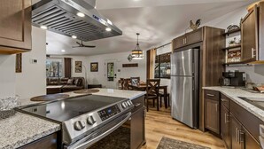 Une cuisine moderne équipée d’une cuisinière, d’un four et d’un réfrigérateur en acier inoxydable, de meubles de rangement en bois et d’un coin repas avec une table et des chaises.