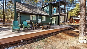 A two-story cabin with a deck, outdoor seating, and a view of the surrounding forest. - Pine Del | 3BR/2BA | Spend Spring in Flagstaff! (Flagstaff)