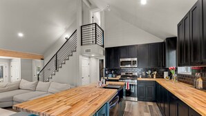 A modern kitchen with dark cabinets, a wooden countertop, and a built-in oven. - Pine Del | 3BR/2BA | Spend Spring in Flagstaff! (Flagstaff)
