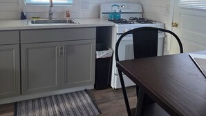 Une cuisine avec un plafond en bois, un évier, des placards, une cuisinière, un four à micro-ondes et une chaise.