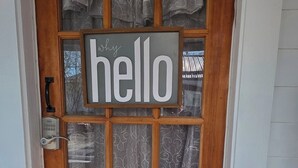Une porte en bois avec une pancarte indiquant « bonjour », une boîte aux lettres et un paillasson.
