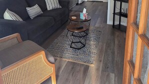Un salon avec un ventilateur de plafond, un canapé, une table basse et un téléviseur.