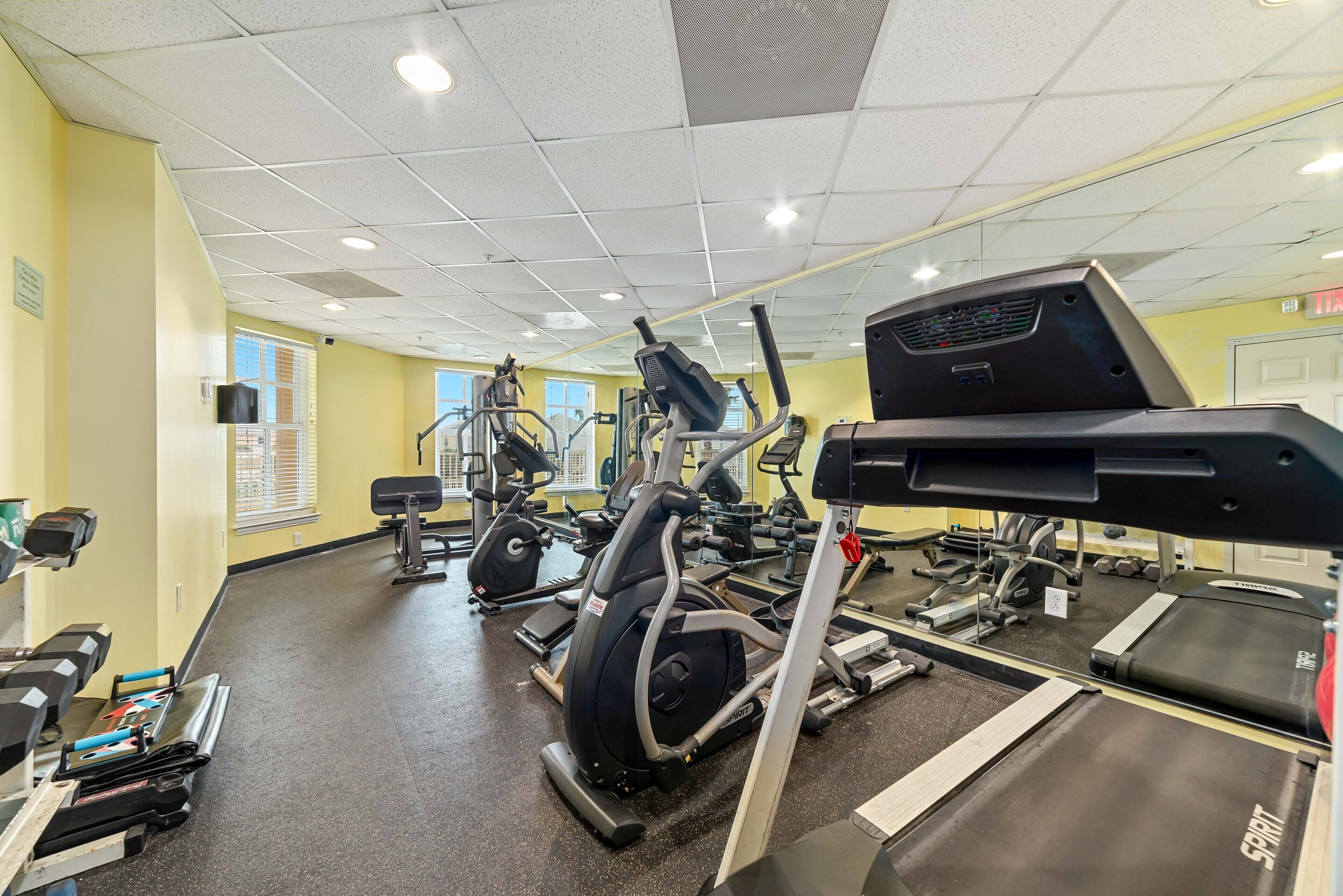 Une salle de sport équipée de divers appareils d’exercice, notamment des tapis de course, des vélos d’appartement et des appareils de musculation.