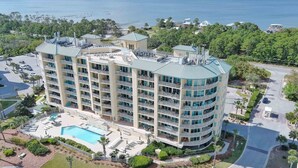 A multi-story hotel with a swimming pool, surrounded by greenery and a view of the sea. - ESCAPE TO THE INDIES CONDO IN FORT MORGAN ALABAMA! (Gulf Shores)