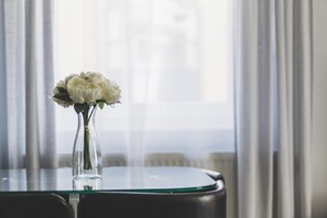 A clear glass vase with white flowers on a glass table.
