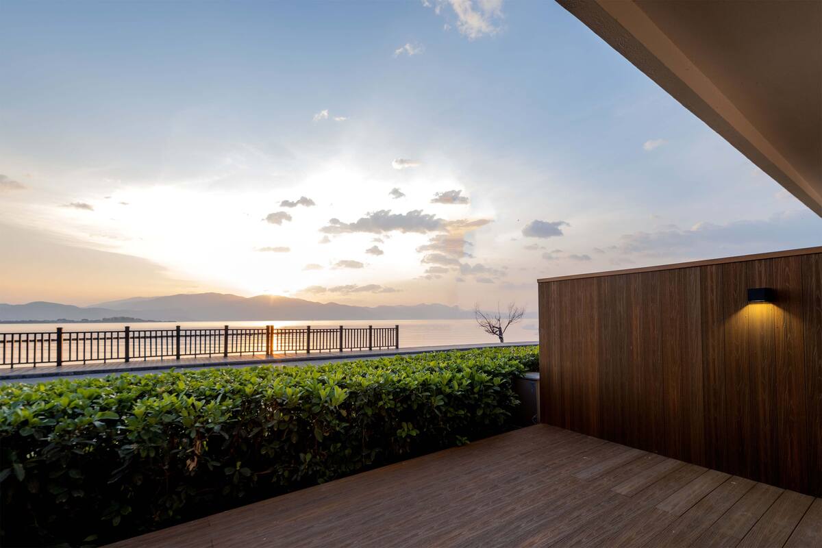 Une terrasse en bois offrant une vue sur l’eau et les montagnes.