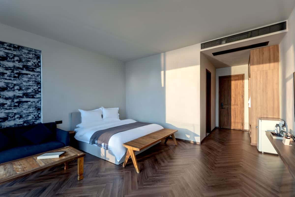 Une chambre d’hôtel moderne, équipée d’un lit, d’une banquette, d’un canapé et d’une table basse.