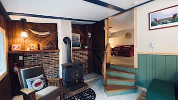 A cozy living room with a fireplace, a wooden bench, a sofa, and a staircase leading to another room.