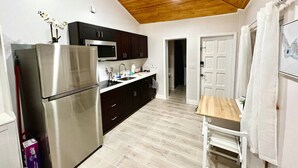 Una cocina con refrigerador, microondas y gabinetes oscuros.