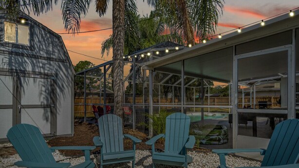 A patio area with Adirondack chairs, a fire pit, and a covered seating area with string lights.