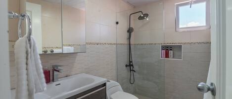 Une salle de bain moderne équipée d’une douche, de toilettes et d’un lavabo.