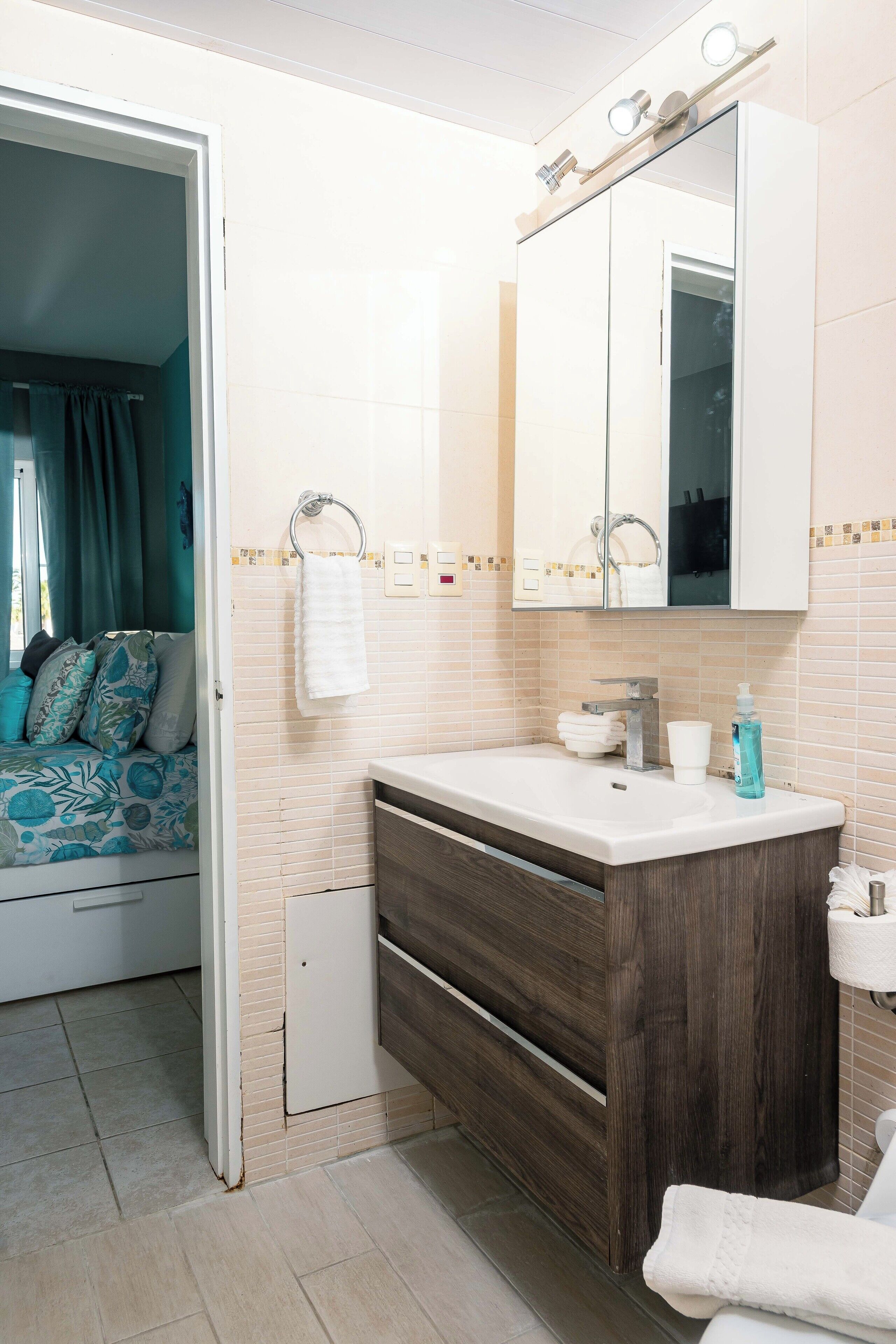 Une salle de bain avec un lavabo, un miroir et un porte-serviettes.